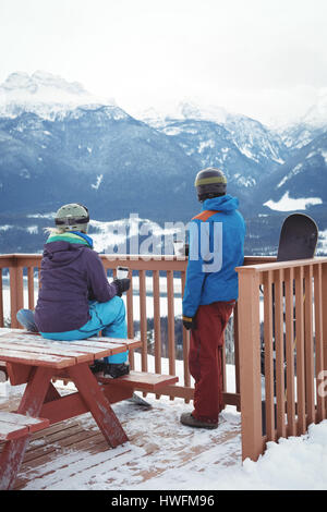 Rückansicht des Paares durch Geländer gegen schneebedeckte Berge im winter