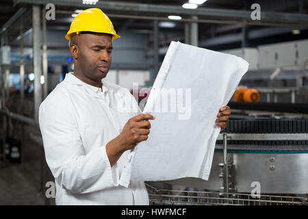 Schweren männlichen Arbeitnehmer Anweisungen in Saft Fabrik lesen Stockfoto