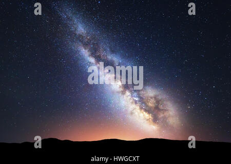 Milky Way. Fantastische Nachtlandschaft mit hellen Milchstraße Himmel voller Sterne, gelbe Stadt Lichter und Berge. Malerische Szenerie mit unserem Universum. S Stockfoto