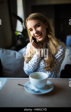 charmante Lady mit schönen Lächeln Gespräch am Mobiltelefon beim Sitzen im Café in der Mittagspause Stockfoto