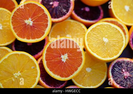 Bunte Orangen, Blutorangen und Cara Cara Orangen halbieren auf einem Stein Hintergrund Stockfoto