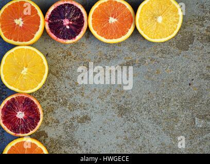 Bunte Orangen, Blutorangen und Cara Cara Orangen halbieren auf einem Stein Hintergrund Stockfoto