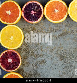 Bunte Orangen, Blutorangen und Cara Cara Orangen halbieren auf einem Stein Hintergrund Stockfoto