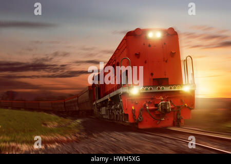 Güterzug mit Güterwagen mit Kohle bei Sonnenuntergang Stockfoto