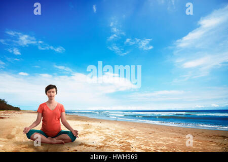 Asiatische schwangere Mutter tun Yoga am Strand Stockfoto
