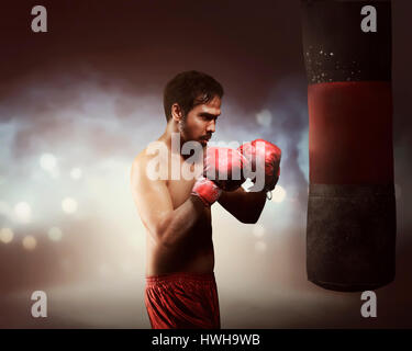Männliche asiatische Boxer Mann Training mit Boxsack in Lichtblitze Stockfoto