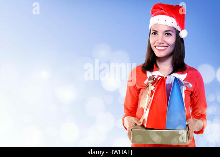 Asiatische Frau Santa Hut hält Geschenk mit bunten Weihnachten Hintergrund Stockfoto