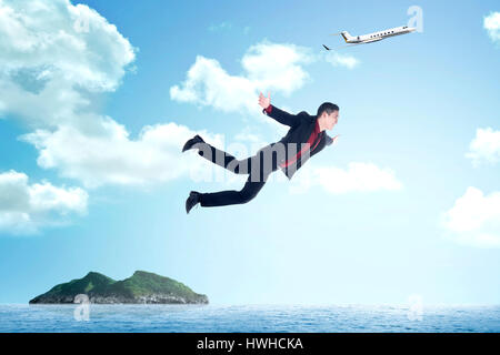 Business-Mann springt vom Flugzeug auf die Insel Stockfoto