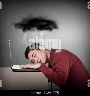 Business-Mann schlafen vor seinem Laptop mit Regenwolke über dem Kopf Stockfoto