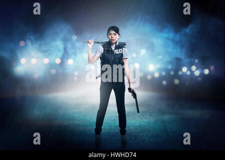 Hübsche Frau in der Polizei Weste holding Baseball Bat als Waffe Stockfoto