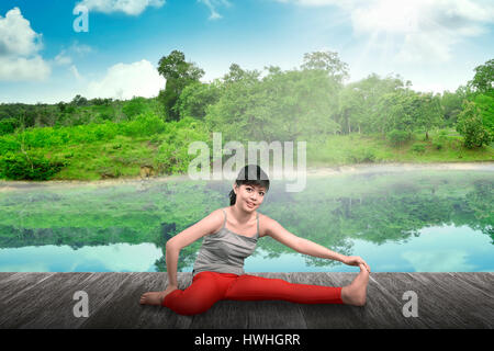 Junge asiatische Frau übt Yoga am Bergsee Stockfoto