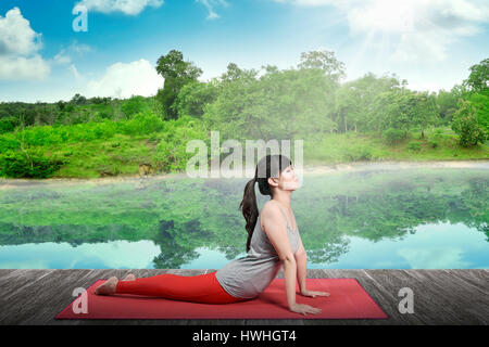 Junge asiatische Frau übt Yoga am Bergsee Stockfoto