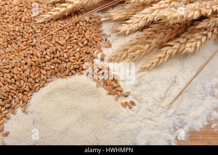 Körner, Ähren und Mehl auf einem Holztisch. Konzept der Zubereitung von Essen aus Getreide. Rustikaler Hintergrund. Textfreiraum Stockfoto
