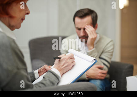 Psychiaterin gegenüber ihrer depressiven Patientin saß und ihm Fragen notwendig für die Ausfüllung der Gesundheitskarte Stockfoto