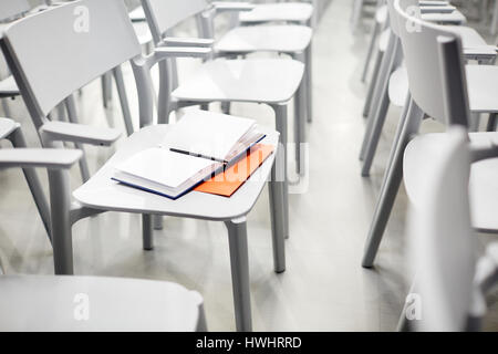 Geöffneten Notizbuch und Stift auf Stuhl im leeren Saal Stockfoto