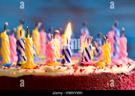 Nahaufnahme von einem Kuchen mit einigen unbeleuchteten Kerzen und nur eine brennende Kerze nach dem Kuchen Ausblasen Stockfoto