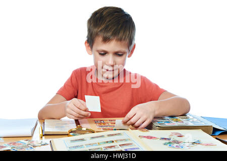 Junge mit seiner Sammlung von alten Briefmarken isoliert weiß Stockfoto