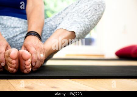 Detail der Reife Frau in Yoga-Pose sitzt. Füße im Fokus Stockfoto