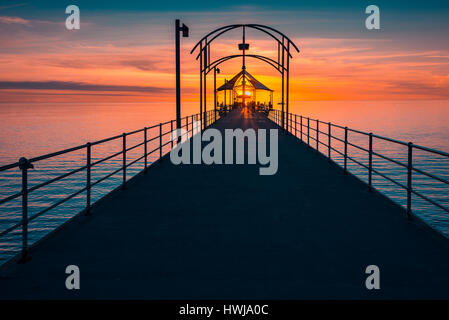 Menschen zu Fuß entlang der Brighton Pier bei Sonnenuntergang Stockfoto