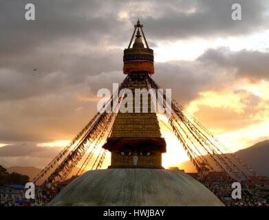 Boudhanath Stupa mit Augen von Buddha und kaskadierende Gebetsfahnen in tibetischen Enklave von Kathmandu, Nepal mit spektakulären Sonnenuntergang im Hintergrund Stockfoto