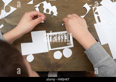 junge macht Origami - Auto und Familie, Kinder, Eltern, ich liebe dich Text, Draufsicht auf Holz Hintergrund Stockfoto