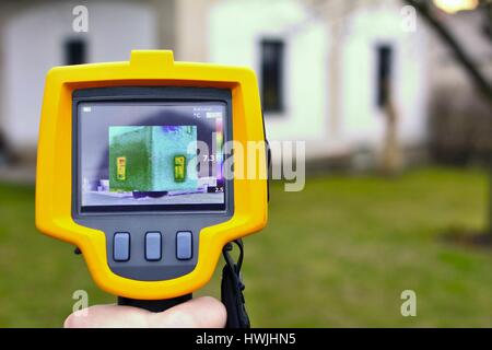 Aufnahme Wärmeverlust des Hauses mit Infrarot-Wärmebildkamera in der Hand. Stockfoto