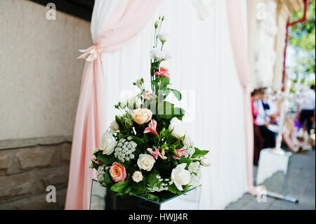 Blumenstrauß auf Spiegelwürfel gegen Bogen Hochzeit Zeremonie. Stockfoto