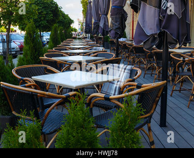 Leere Tabellen des Sommer-Café auf der Straße vor der Eröffnung in den frühen Morgenstunden. Fokus auf den Vordergrund. Stockfoto