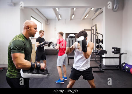 Handsome fit hispanic Mann mit seinem persönlichen Trainer Boxen. Athlet Boxer tragen Boxhandschuhe kämpfte im Box-Gym. Stockfoto