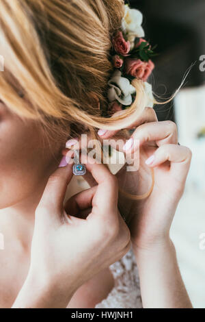 Hübsche junge Braut mit Blumen im Haar tragen Ohr-ring Stockfoto