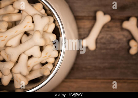 Draufsicht auf eine Schüssel mit knackigen entbeint geformte Hundekuchen, auf einem alten Holzboden. Stockfoto