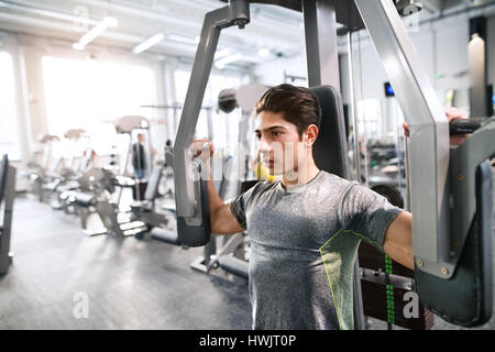 Junge spanische Fitness Mann im Fitness-Studio arbeitet über Schmetterling Fitnessgerät mit Gewichten, Muskeln Stockfoto