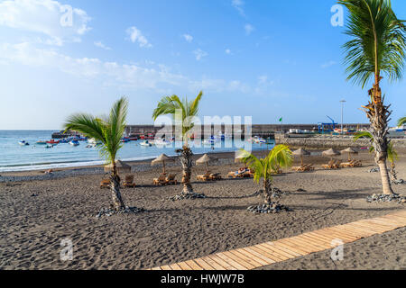 Palmen auf schwarzen vulkanischen Sandstrand im Hafen von San Juan, Teneriffa, Spanien Stockfoto