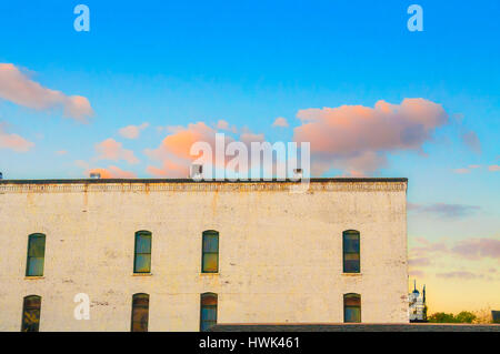 Einem gelben Ziegeln Industriegebäude gegen einen wunderschönen Sonnenuntergang Himmel gesehen Stockfoto