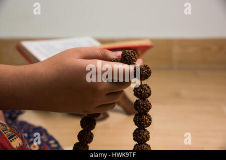 Nahaufnahme Bild von Hand dabei Meditation mit Rudraksha Mala oder Rosenkranz Perlen, selektiven Fokus Stockfoto