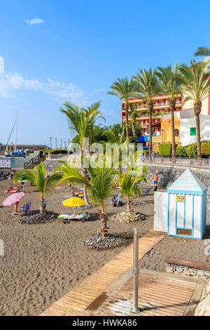 Strand von SAN JUAN, Teneriffa - 15. November 2015: Sonnenliegen Wuth Sonnenschirme am Strand mit Palmen in der Stadt San Juan auf Teneriffa, Spanien. Stockfoto