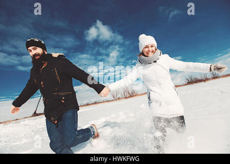 Konzept der glückliches Familienleben, Winterurlaub, Wandern. Mann und Frau überfahren schönen blauen Himmelshintergrund über schneebedecktes Feld Stockfoto