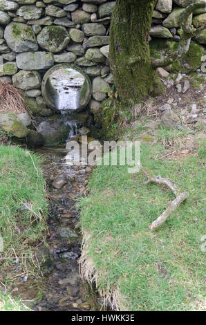 Wasserrohr Abflüsse in der Mauer aus Stein um ein Feld Stockfoto