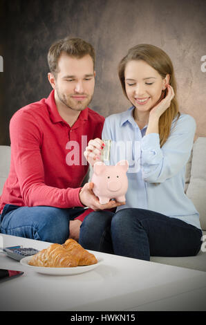 Junges Paar spart ins Sparschwein. sparen Geld paar Sparschwein Haushaltsbudget Ehe Kosten Konzept Stockfoto