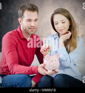 Junge Ehe bringt Einsparungen in Sparschwein. sparen Geld paar Sparschwein Haushaltsbudget Ehe Kosten Konzept Stockfoto