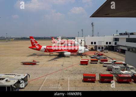 BANGKOK, THAILAND - 3. März 2014: Ausladen des Gepäcks vom Flugzeug Air Asia in Bangkok Flughafen. Air Asia Company ist die größte low-cost Fluglin Stockfoto