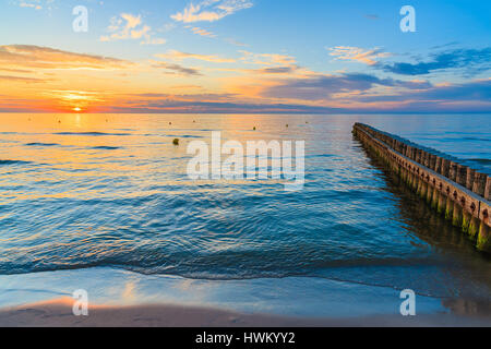 Sonnenuntergang über Meer mit hölzernen Wellenbrecher im Vordergrund Leba Strand, Ostsee, Polen Stockfoto