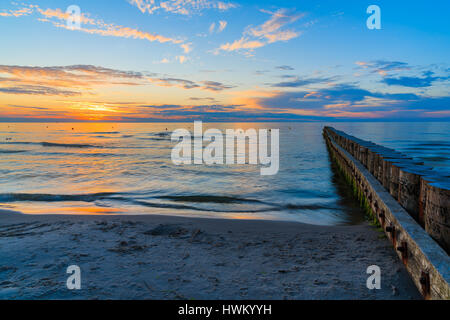 Sonnenuntergang über Meer mit hölzernen Wellenbrecher im Vordergrund Leba Strand, Ostsee, Polen Stockfoto