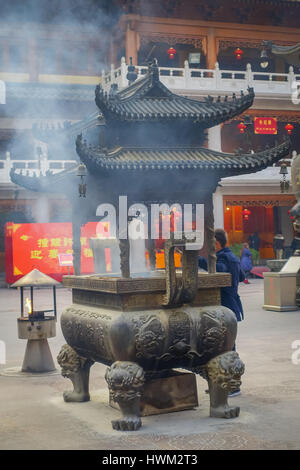 SHANGHAI, CHINA: Große traditionelle Metallstruktur mit schönen Schnitzereien, Mann, der inneren Feuer und Rauch heraus, Jing'an Tempel Viertel Stockfoto