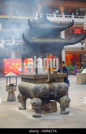 SHANGHAI, CHINA: Große traditionelle Metallstruktur mit schönen Schnitzereien, Mann, der inneren Feuer und Rauch heraus, Jing'an Tempel Viertel Stockfoto