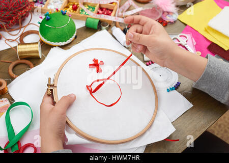 Junge auf Reifen, Hand Closeup und rotes Band auf weißen Textilien bestickt erfährt, Nähen, job, Ausbildung, Handarbeit und Kunsthandwerk-Konzept Stockfoto