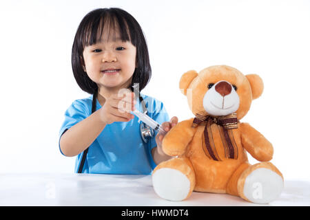 Asiatische chinesische Arzt wenig Mädchen geben Injektion zu Teddybär in isolierten weißen Hintergrund. Stockfoto