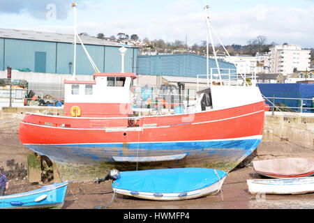 Kleiner Trawler Schiff rot weiß lackiert und blau vertäut Deich bei Ebbe in Teignmouth, Devon England Stockfoto