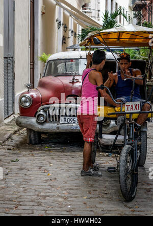 Havanna, Kuba - 5. Januar 2016: Typische Szene einer der Straßen im Zentrum von La Havanna - alte Autos und Rikscha Fahrrad taxi Stockfoto