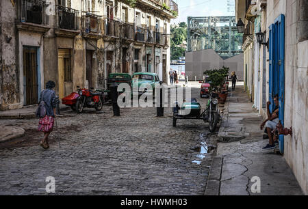 Havanna, Kuba - 5. Januar 2016: Typische Szene einer der Straßen im Zentrum von La Havanna - Kolonialarchitektur, Autos und Menschen herumlaufen Stockfoto